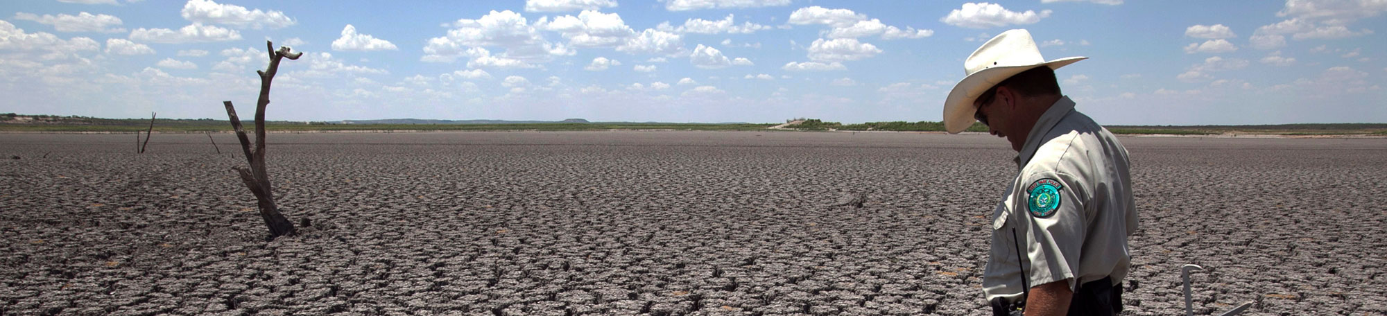 A ranger examines a drought-cracked landscape