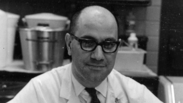 Anthony P. Amarose, in a lab coat and glasses, smiles.