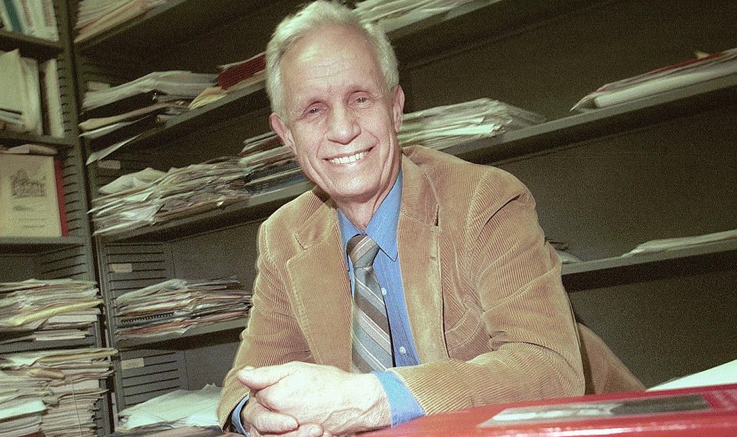 David Bevington smiles while sitting in the archives.