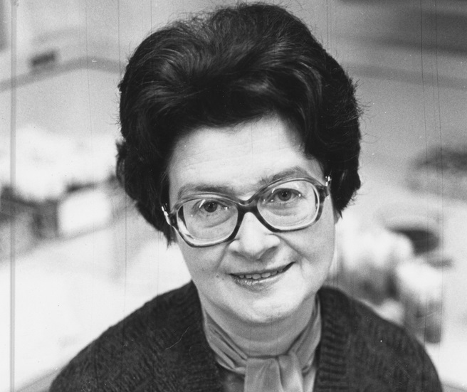 Janice Spofford, wearing glasses, tilts her head and smiles.