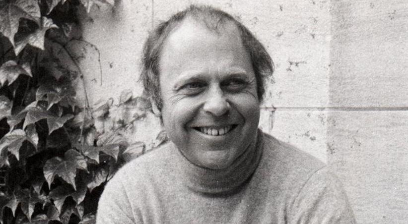 Marshall D. Sahlins smiles wide in front of building covered with plants.