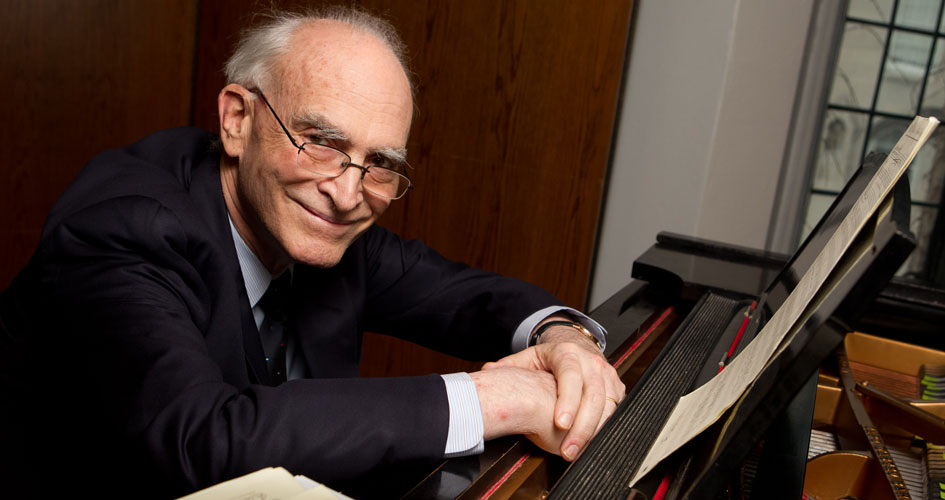 Phillip Gossett smiles while leaning against a piano.