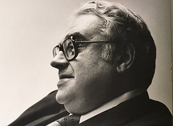 Robert Uretz, wearing glasses, looks to the side.