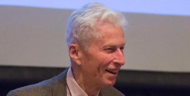 Roger Hildebrand smiles as he gives a lecture with a projector.