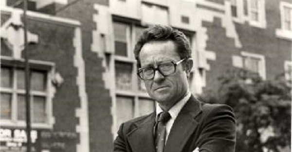 Gerald D. Suttles, wearing glasses, stands in front of building.