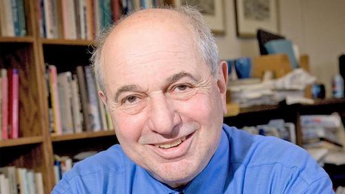 Richard P. Taub, in front of bookshelf, smiles.