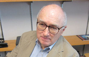 Peter O. Vandervoort, wearing glasses, sits in front of a desk and turns to the camera.