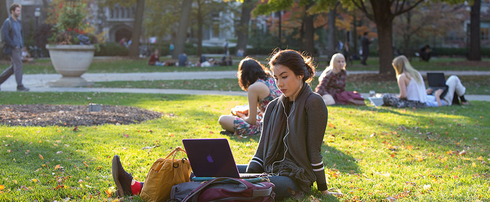 student sits in quad with laptop