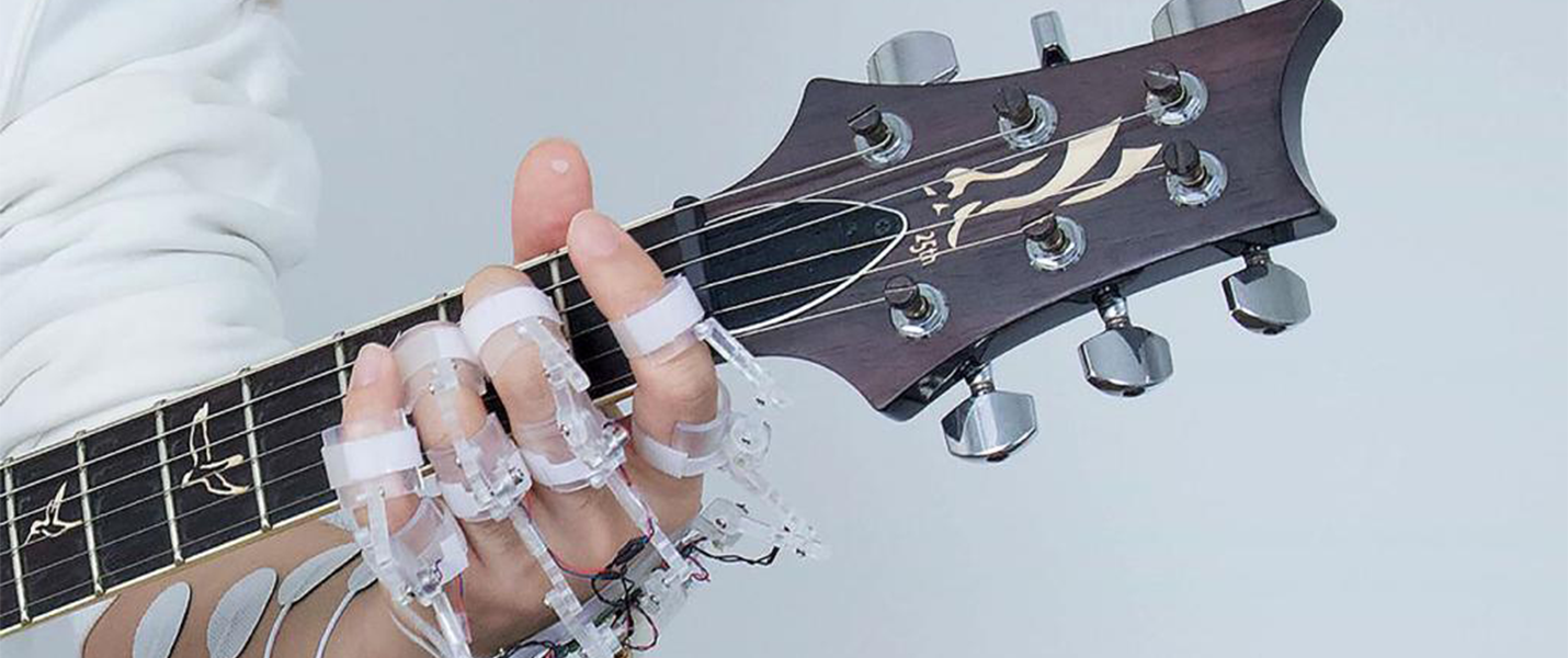 a hand wearing a device playing guitar