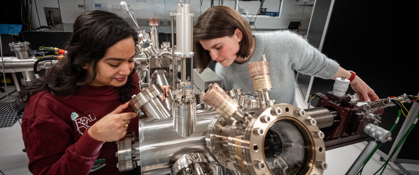 Atreyie Ghosh (left) and Sarah King look at samples being transferred into an ultrahigh vacuum chamber for investigation with a time-resolved photoemission electron microscope.