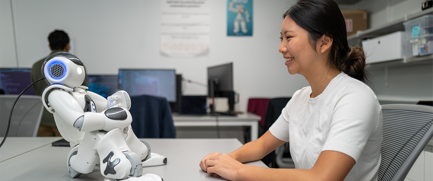 woman interacting with small robot sitting on a table