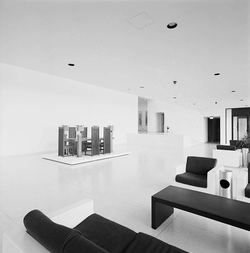 Smart lobby with white framed furniture, potted plants, and a display of furniture designed by Frank Lloyd Wright