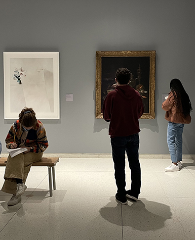 Three college students write in notebooks in a museum gallery