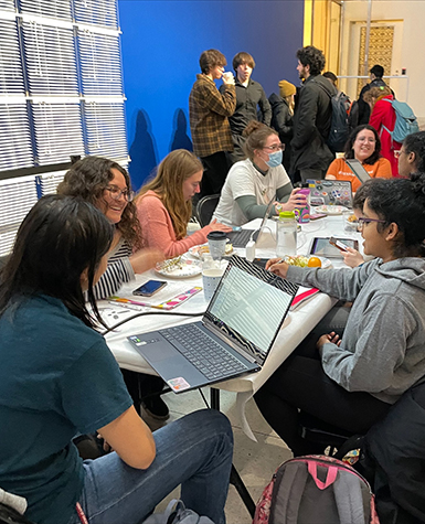 Students sit around a table studying and talking
