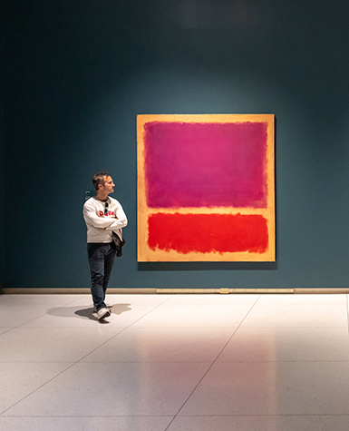 A person walking by a painting by Mark Rothko