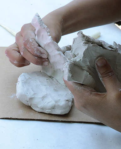 Close-up view of a child's hands as they play with clay