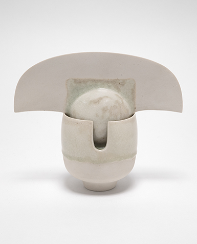 A white porcelain sculpture of a ball with a fan-like crown resting in a cup