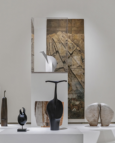 Ceramic sculptures with a variety of organic forms displayed on a series of platforms in a museum