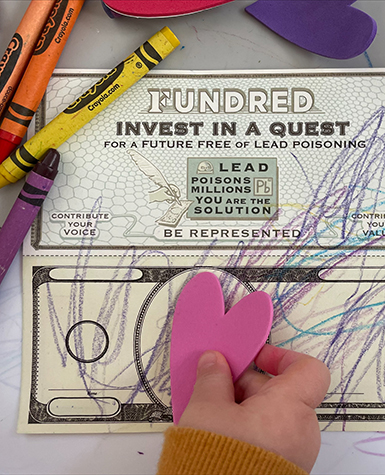 A child places a pink heart on a fundred dollar bill