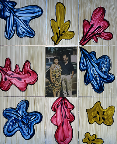 A small photo of a couple is set in a hand-painted frame with colorful flowers