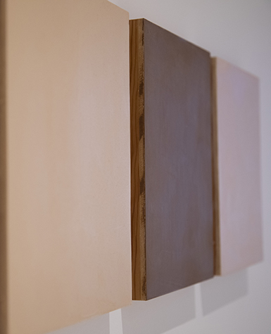 Three painted panels of different flesh-colored hues hang side-by-side