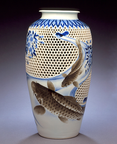 A reticulated vase with two carp swimming among fallen cherry blossoms