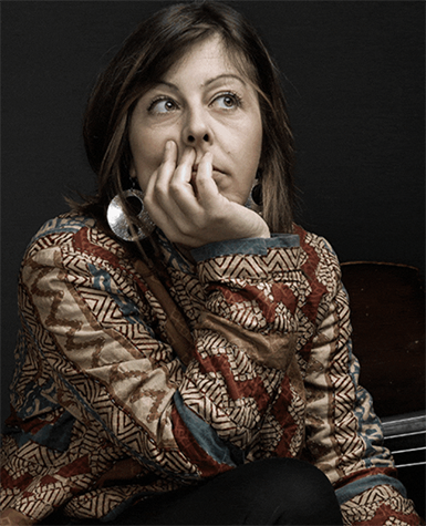 An image of Silvia Bolognesi kneeling with an upright bass laid down behind her