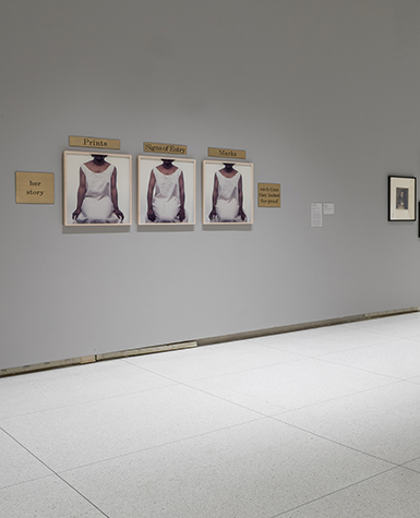Lorna Simpson's photo tryptic Three Seated Figures installed on a gray gallery wall