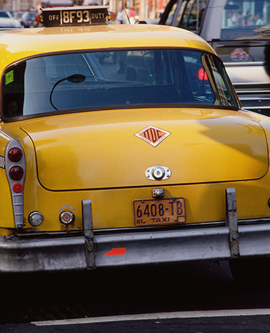 Photo of an orange polygon bumper sticker on a yellow taxi cab