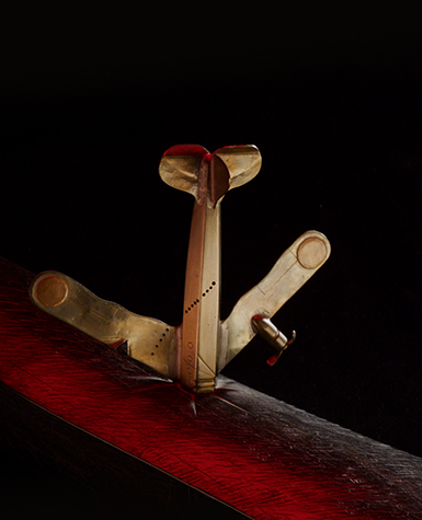 A sculpture of a metal airplane standing nose-down on a block of wood