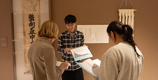 Three students engaged in discussion in the galleries