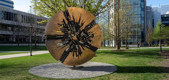 A bronze disc sculpture in a campus quad